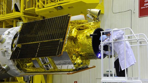 טכנאים מחברים את הלוויין לשלב העליון של הטיל. הגוף הגלילי הנראה בתמונה הוא מגן למצלמת הלוויין צילום: RSC ENERGIA